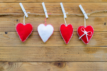 Fototapeta premium three red felt hearts and one white. symbol for a family, love. On wooden background