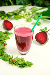 beet red healthy smoothie on white table with leaf and beetroot on background