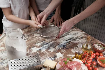 Foto op Canvas Mom with children preparing the dough for pizza. Hands of mother and her children. Cooking with kids. Close-up © yusev