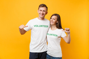 Portrait of young colleagues couple in white t-shirt with written inscription green title volunteer...