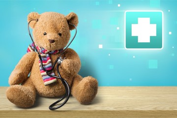 Adorable teddy bear, isolated on white, holding a stethoscope.