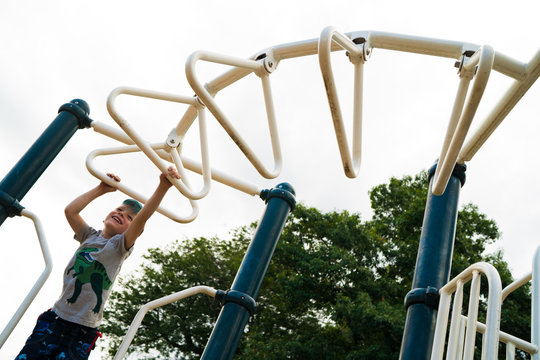 Smiling boy playing on monkey bars in park