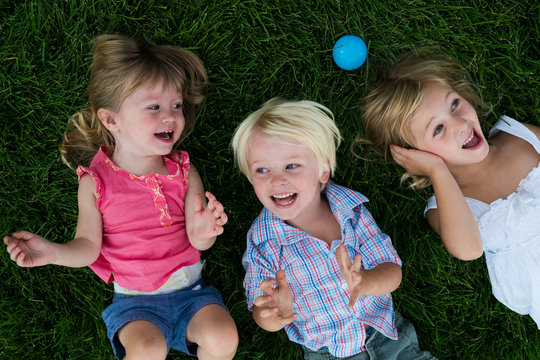 Overhead view of cheerful children lying on grass