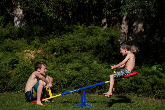 Cheerful sibling playing on seesaw in park