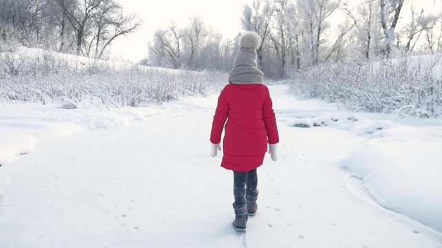 Little girl walking in winter fairy ice forest.
