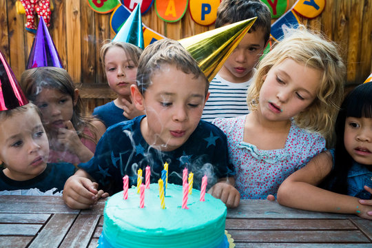 Boy blowing out candles at birthday party