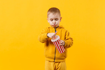 Fototapeta premium Little fun cheerful kid boy 3-4 years old wearing yellow clothes hold cup of soda isolated on orange wall background, children studio portrait. People, childhood lifestyle concept. Mock up copy space.