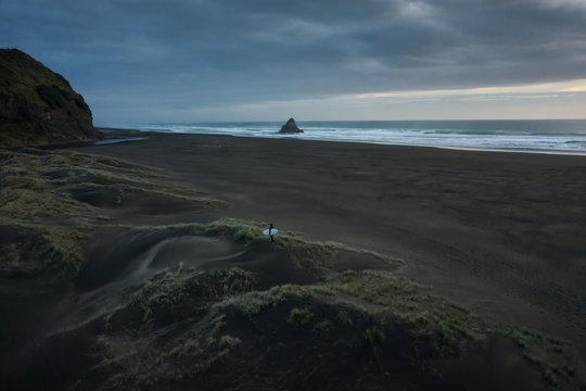 Man carrying surfboard while walking on beach