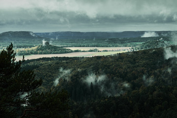 Deadpan dark misty rainy morning landscape with the sand rocky montains in Czech Saxon Switzerland in autumn colors