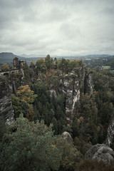Deadpan dark misty fog mountains from viewpoint of Bastei in Saxon Switzerland, Germany to the mountains at sunrise in the morning fog, National park Saxon Switzerland
