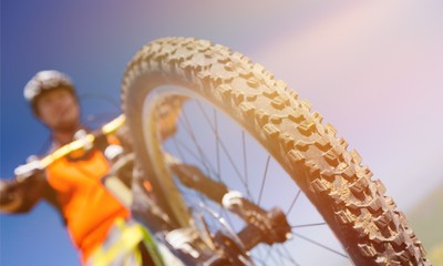Young man riding a bicycle outdoors. Close-up bicycle wheel