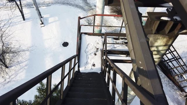 Descend the metal stairs from the overpass at the factory