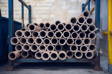 An industrial stack of empty paper cardboard tube rolls waiting to be recycled in a warehouse setting. Industrial waste management. Recycle helping the environment.