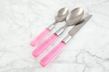 Two spoons and knife on white gray background.