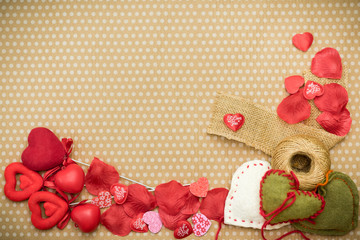 Many red hearts lie on an old cardboard background in white peas.