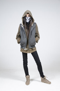 A woman with a skull scary horror mask against a white infinity curve background in a studio. A horror movie urban street character.