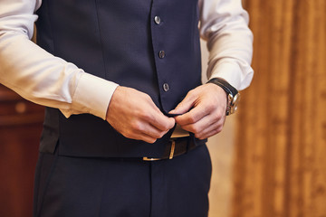 Businessman wears a jacket,male hands closeup,groom getting ready in the morning before wedding ceremony