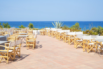 Empty terrace with wooden chairs with sea view outdoors in Greece