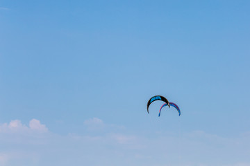 Two kites of kiteboard in the blue sky