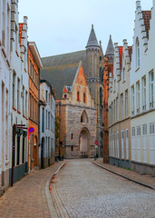 Streets of Bruges in Belgium with its medieval style facades on a cloudy day.