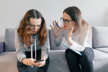 Young woman professional psychologist talking with teenager girl 14, 15 years old sitting in office on sofa. Mental health of child in adolescence