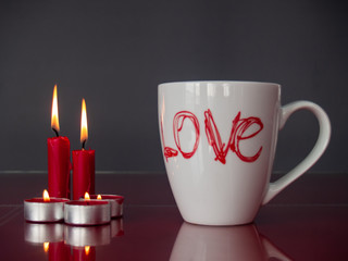 Concept of love Still life with red lit candles and a breakfast cup with the word love
