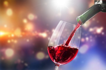 Red wine pouring in glass on  background
