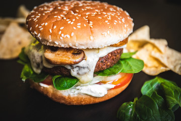 Hamburger vegetarian burger with falafel and vegetables salad tomato champignon and cheese tofu cheese all vegan food with nachos in blurred background