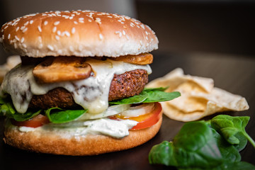 Hamburger vegetarian burger with falafel and vegetables salad tomato champignon and cheese tofu cheese all vegan food with nachos in blurred background