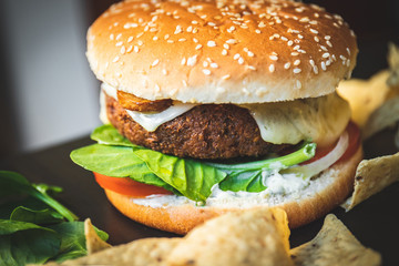Hamburger vegetarian burger with falafel and vegetables salad tomato champignon and cheese tofu cheese all vegan food with nachos in blurred background