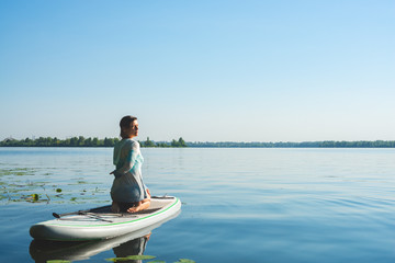 Woman is practicing yoga on a SUP board