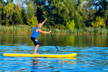 Happy man is training on a SUP board