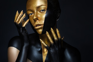 High fashion model with black and gold leather, golden fingers. Isolated on black background Beauty...