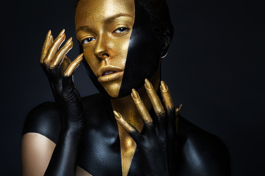 High fashion model with black and gold leather, golden fingers. Isolated on black background Beauty female face, creative make-up.