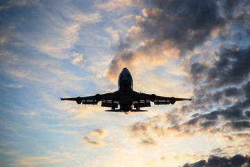 Airplane is landing during a nice cloudy sunrise.