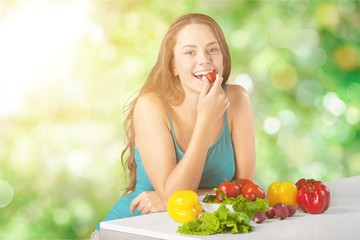 Young woman eating vegetables on blurred kitchen background