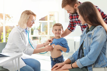 Children's doctor examining little boy with stethoscope in hospital