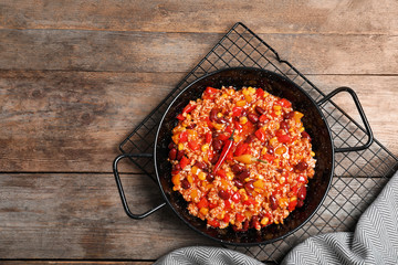 Dish with chili con carne on wooden background, top view. Space for text