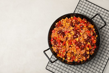 Dish with chili con carne on light background, top view. Space for text