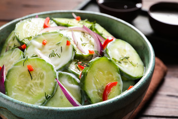 Dish with fresh creamy cucumber salad on table, closeup