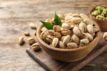  Organic pistachio nuts in bowl on wooden table. Space for text © New Africa