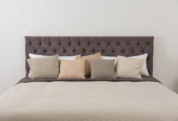 Fototapeta na wymiar Large comfortable bed near light wall in modern room interior