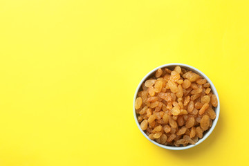 Bowl with raisins and space for text on color background, top view. Dried fruit as healthy snack