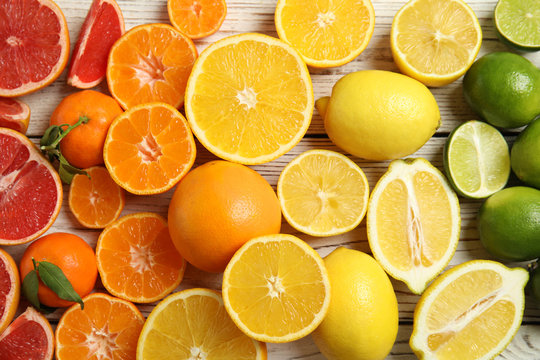 Different citrus fruits on wooden background, top view
