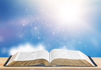 Open book on old wooden table on sky background sunlit