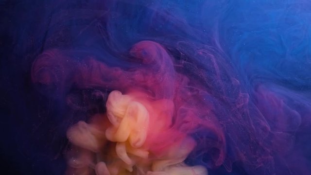 Abstract psychedelic background. Yellow and red ink is poured into blue liquid in slow motion