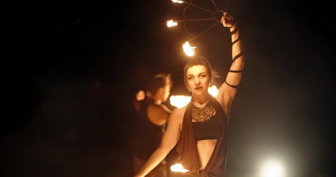 Cool female fire show artist is having a performance, flailing her equipment in darkness - slow motion 4k