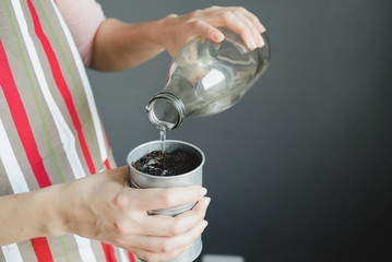 woman hand watering the soil in metal pot, stock photo image