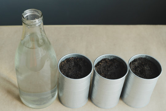 still life of glass bottle and metal pot with soil to planting greens, stock photo image