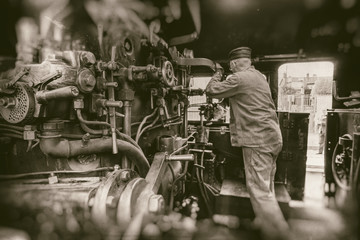 Railway man working on steam train engine  - retro photography